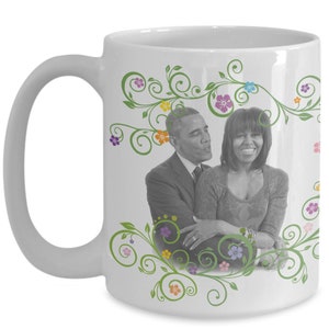 May include: White ceramic coffee mug with a black and white photo of a couple. The photo is surrounded by green vines with colorful flowers.