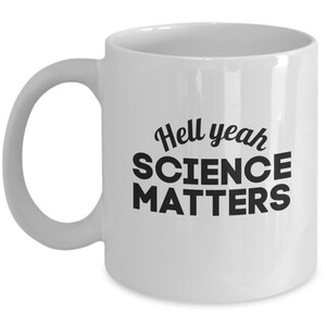 May include: White ceramic coffee mug with black text that reads "Hell yeah SCIENCE MATTERS".