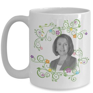 May include: White ceramic coffee mug with a black and white photo of a woman surrounded by green vines and colorful flowers.