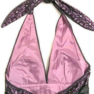 May include: A formal halter dress with a black ruched bodice and a mauve-colored lining. The halter straps and neckline are trimmed with black lace and embellished with small rhinestones. The straps tie at the back of the neck.