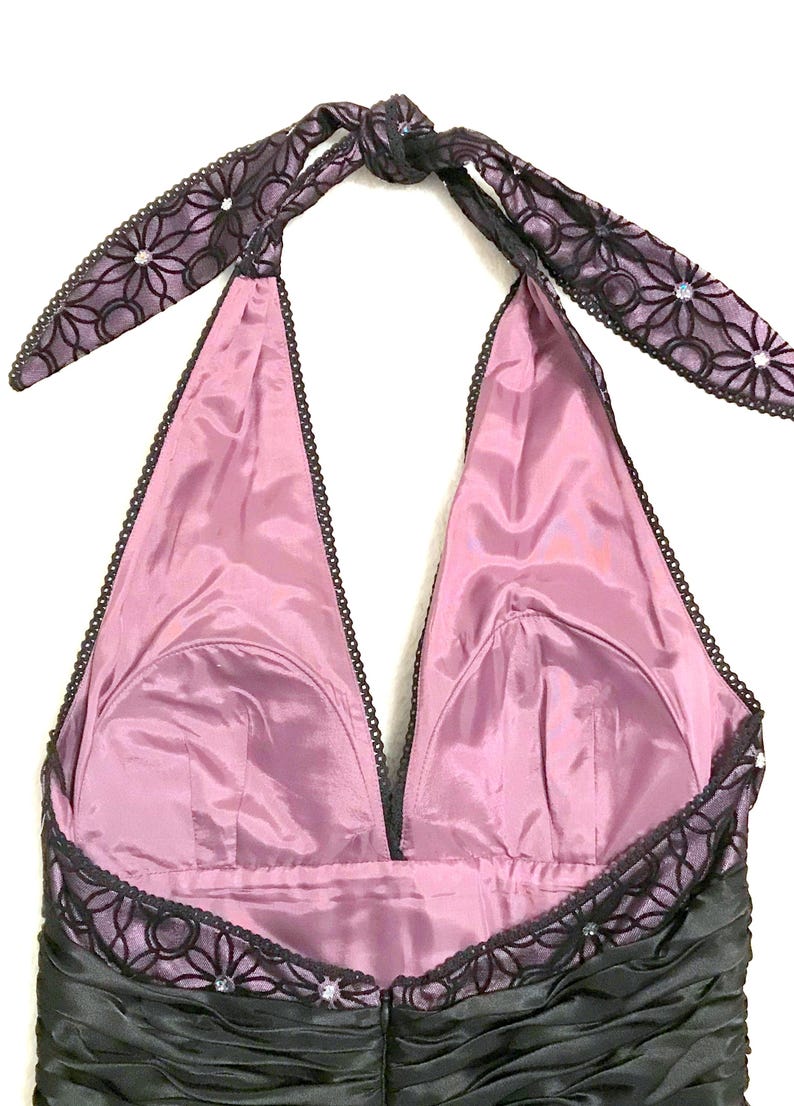 May include: A formal halter dress with a black ruched bodice and a mauve-colored lining. The halter straps and neckline are trimmed with black lace and embellished with small rhinestones. The straps tie at the back of the neck.