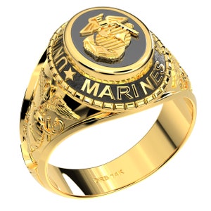 Könnte beinhalten: Ein goldfarbener Ring mit einem schwarzen Emblem, das einen Adler, einen Globus und einen Anker zeigt. Der Ring ist mit "UNITED STATES MARINES" beschriftet und hat aufwendige Seitendetails. Der Ring ist mit "DRS 14K" markiert.
