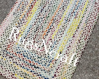 May include: A colorful braided rug with a rectangular shape. The rug is made of multiple strands of yarn in various colors, including red, blue, yellow, and green. The rug has a white background and is woven in a pattern of squares.