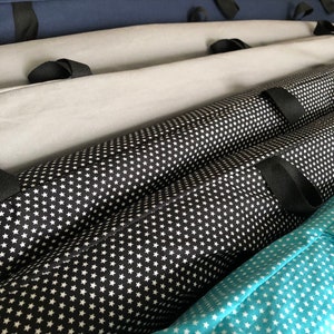 Può includere: Quattro contenitori di stoffa con cinturini neri. I contenitori sono impilati uno sopra l'altro. Il contenitore superiore è blu scuro, il secondo contenitore è grigio, il terzo contenitore è nero con stelle bianche e il contenitore inferiore è turchese con stelle bianche.