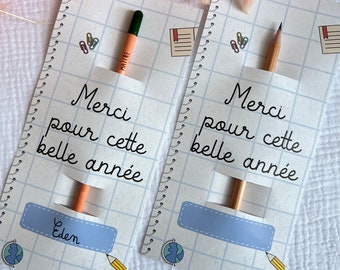 Puede incluir: Dos tarjetas estilo cuaderno con lápices, con el texto "Merci pour cette belle année" y un espacio para un nombre. Las tarjetas tienen un patrón de cuadrícula, con ilustraciones de un globo, un lápiz y útiles escolares. Flores rosas secas en el fondo.