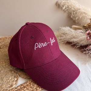May include: A burgundy baseball cap with white embroidery that reads "père-fect".