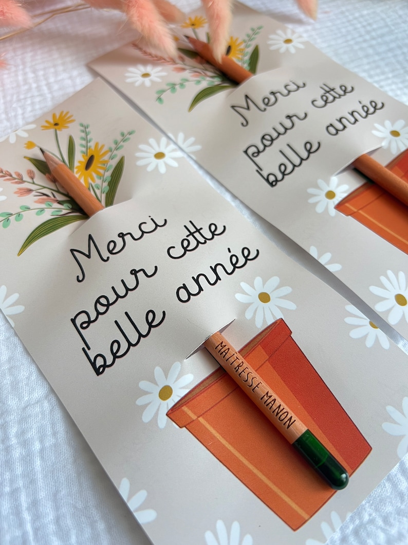 Może przedstawiać: Dwie kartki z kwiatowym wzorem i tekstem "Merci pour cette belle ann&eacute;e", co oznacza "Dziękuję za ten piękny rok". Każda kartka ma oł&oacute;wek wystający z doniczki z napisem "Maitresse Manon" na oł&oacute;wku.