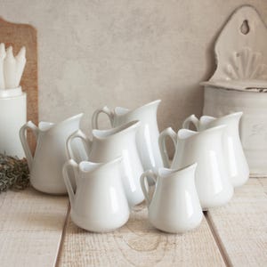 Juego de 7 jarritas pequeñas vintage TRADITION de FRANCE de cerámica blanca.