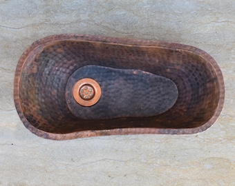 May include: A hammered copper bathtub with a drain in the bottom. The bathtub is oval shaped and has a rustic look.