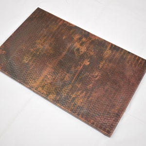 May include: A rectangular copper sheet with a hammered texture and a distressed finish. The sheet has a warm, reddish-brown color with hints of green and black.