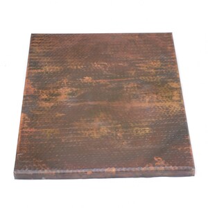 May include: A square copper tabletop with a hammered finish. The copper has a rustic, aged look with brown and orange tones.
