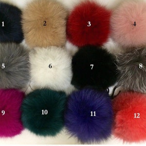 May include: Twelve different colored faux fur pom poms. The pom poms are arranged in four rows of three. The pom poms are in the following colors: black, beige, red, pink, gray, white, black, gray, magenta, green, blue, and orange.