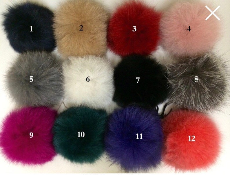 May include: Twelve different colored faux fur pom poms. The pom poms are arranged in four rows of three. The pom poms are in the following colors: black, beige, red, pink, gray, white, black, gray, magenta, green, blue, and orange.