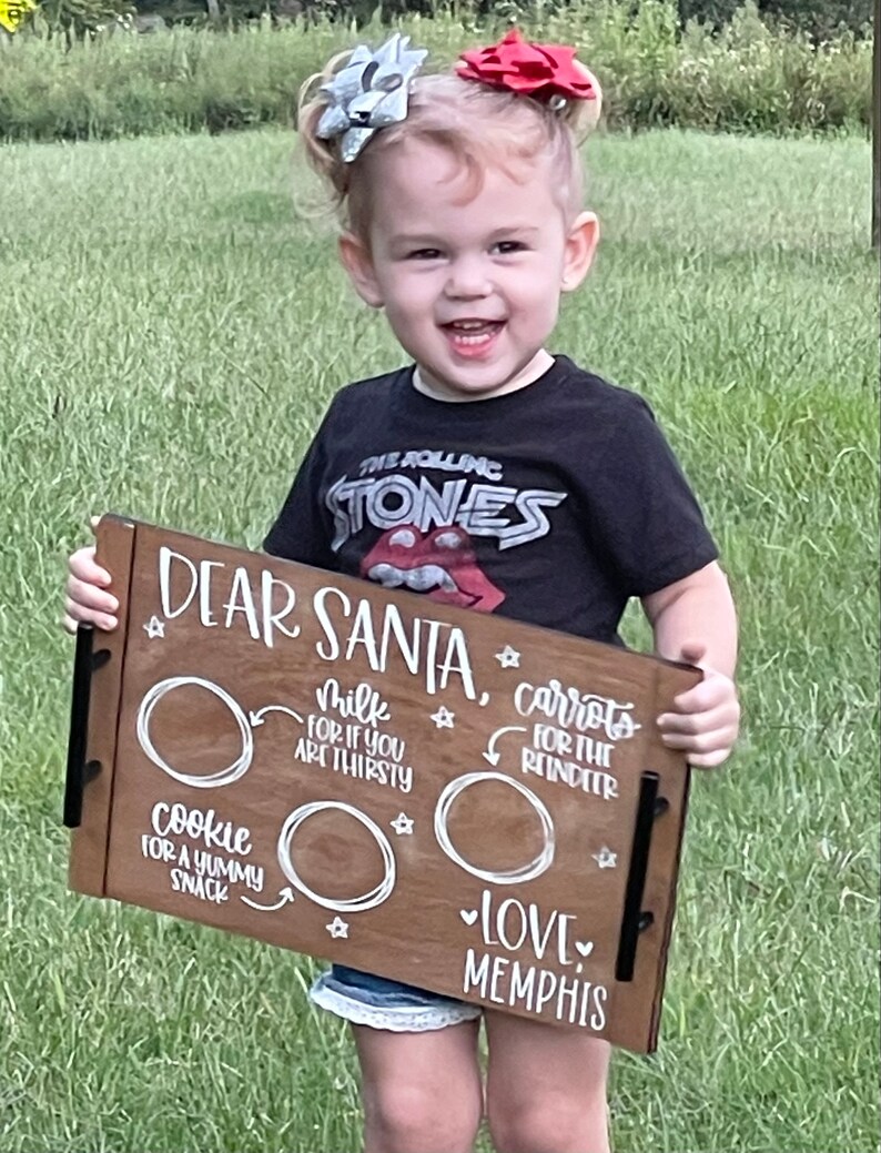 May include: A wooden tray with the words "Dear Santa" and a list of items for Santa to bring: cookies, milk, and carrots for the reindeer. The tray is decorated with stars and hearts. The text "Love Memphis" is written at the bottom of the tray.