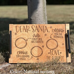 May include: A wooden tray with a "Dear Santa" message and three circles for placing treats. The circles are labeled "carrots for the reindeer", "milk for if you are thirsty", and "cookie for a yummy snack". The tray also has the text "Love, The Beavers" and is decorated with stars.