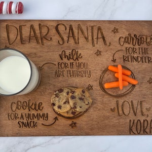 May include: A wooden tray with the words "Dear Santa" and "Love, Kora" engraved on it. The tray is decorated with a glass of milk, a cookie, and carrots for the reindeer.