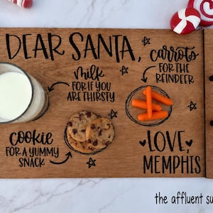 May include: A rectangular wooden serving tray with black metal handles, featuring the black text DEAR SANTA, milk for if you are thirsty, cookie for a yummy snack, carrots for the reindeer, and LOVE, MEMPHIS, with illustrations of stars.