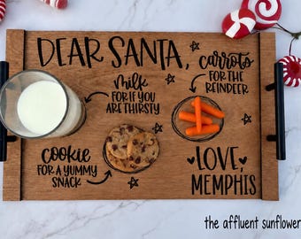 May include: A rectangular wooden serving tray with black metal handles, featuring the black text DEAR SANTA, milk for if you are thirsty, cookie for a yummy snack, carrots for the reindeer, and LOVE, MEMPHIS, with illustrations of stars.