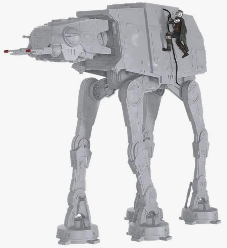 May include: A light gray plastic AT-AT walker toy featuring a four-legged design with a head-mounted cannon. A small, detailed figure in dark armor is attached to the side of the walker, connected by a black cable, showcasing intricate mechanical details.