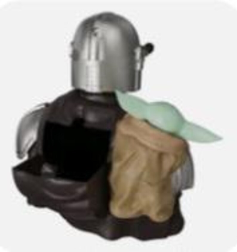 K&ouml;nnte beinhalten: Eine dekorative Figur, die einen silberfarbenen, behelmten Charakter in dunkler R&uuml;stung zeigt, mit einer kleinen, hellgr&uuml;nen, gro&szlig;ohrigen Kreatur in einer beigefarbenen Tasche an der Seite. Die Figur verf&uuml;gt &uuml;ber einen ausgeh&ouml;hlten Mittelteil.