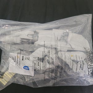 May include: A white plastic Star Wars The Mandalorian Grogu toy set sealed in a clear plastic bag. The packaging features black text including the title, warning labels, and battery requirements for two AAA batteries. The toy includes a figure.