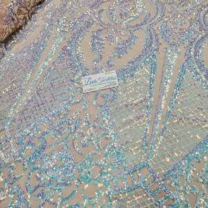 May include: Pale blue iridescent sequins on a sheer mesh fabric with a damask pattern. The fabric is perfect for creating a glamorous and sparkly look for dresses, tops, and other garments.