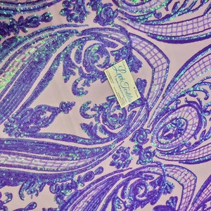 May include: Purple iridescent sequins on a pink fabric with a damask pattern. The fabric is for sale and the business card for "Levi Textiles" is visible in the image.