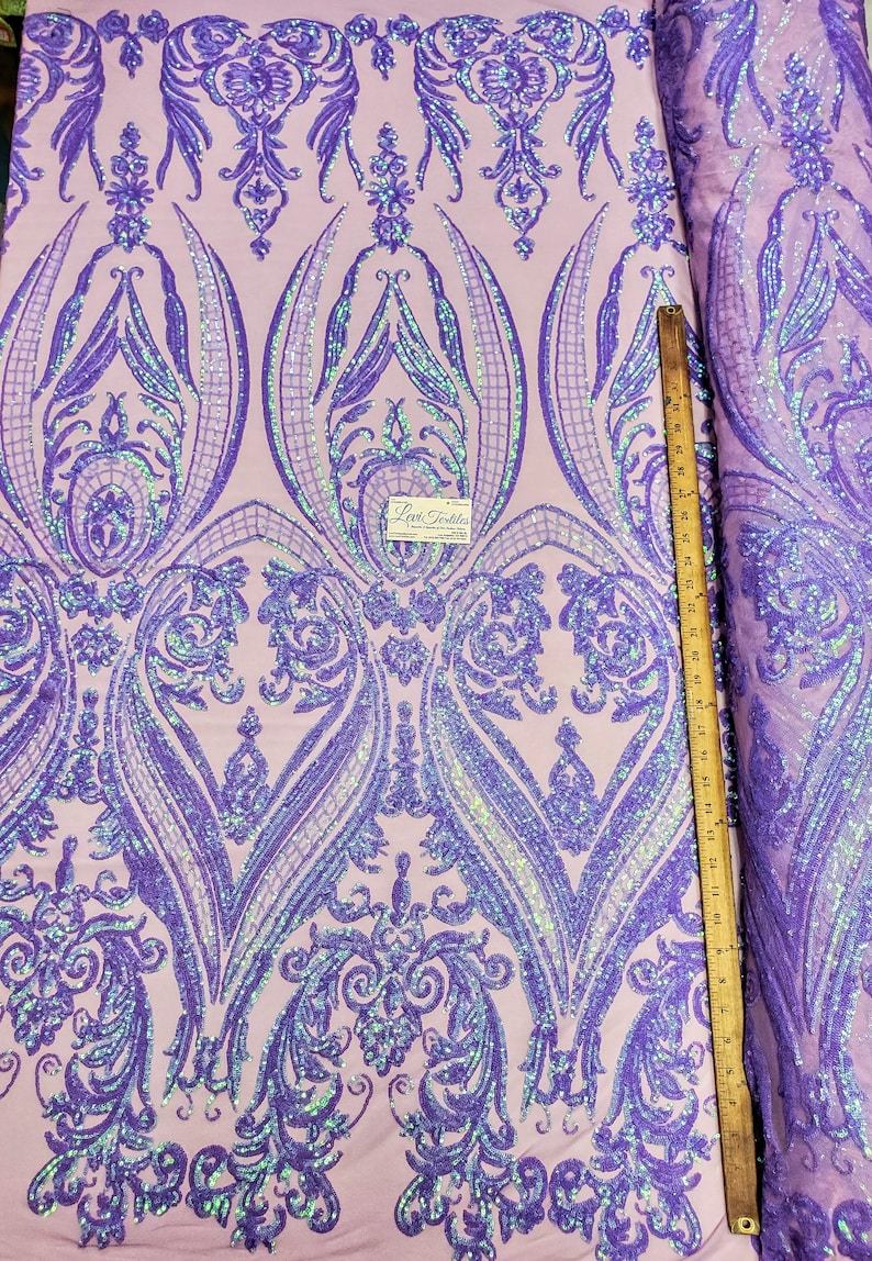 May include: Purple iridescent sequins on a pink mesh fabric with a damask pattern. The fabric is measured with a ruler in inches.