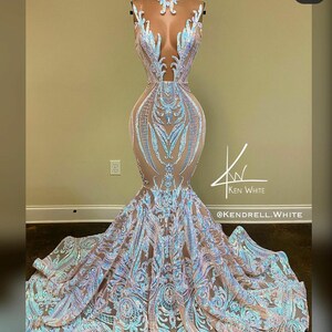 May include: A long, flowing, light blue and silver sequined gown with a mermaid silhouette. The gown features a plunging neckline and a sheer bodice with intricate floral patterns. The skirt is full and flowing, with layers of sequins that shimmer in the light. The gown is perfect for a formal event, such as a prom or wedding.