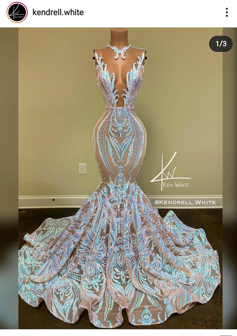 May include: A long, flowing, light blue and silver sequined gown with a mermaid silhouette. The gown features a plunging neckline and a sheer bodice with intricate floral patterns. The skirt is full and flowing, with layers of sequins that shimmer in the light. The gown is perfect for a formal event, such as a prom or wedding.