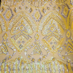 May include: Yellow and silver sequined fabric with a geometric pattern. The fabric is on a ruler that measures 81 cm.
