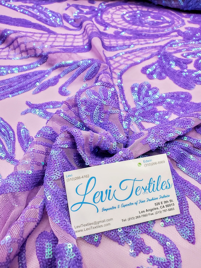 May include: Purple iridescent sequins on a sheer lavender fabric. The fabric is draped over a business card that reads "Levi Textiles Importer & Exporter of Fine Fashion Fabrics" with contact information.