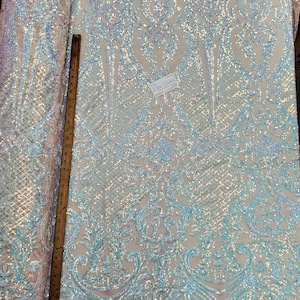 May include: Pale blue iridescent sequin fabric with a damask pattern. The fabric is 30 inches wide and is perfect for crafting and sewing projects.