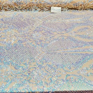 May include: White iridescent fabric with a floral pattern. The fabric is covered in sequins that shimmer in the light.