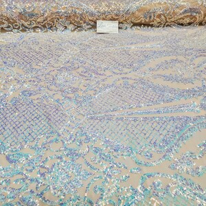 May include: A close-up of iridescent blue and purple sequins on a sheer mesh fabric. The sequins are arranged in a floral pattern.