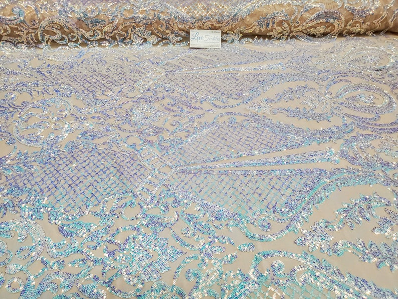 May include: A close-up of iridescent blue and purple sequins on a sheer mesh fabric. The sequins are arranged in a floral pattern.