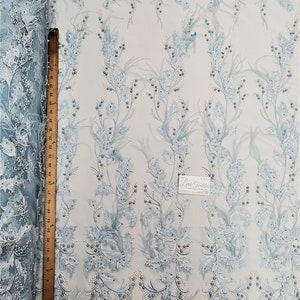 May include: Light blue beaded lace fabric with a floral pattern and feather accents. The fabric is shown with a ruler for scale.