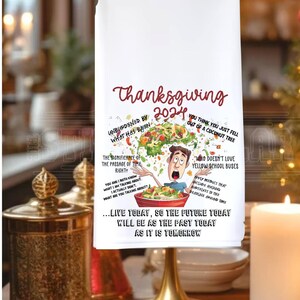 May include: White kitchen towel with a Thanksgiving 2024 design. The design features a cartoon man with a salad bowl on his head, surrounded by food and text. The text includes "Unburdened by what has been", "The significance of the passage of time right?", "You think you just fell out of a coconut tree", "Who doesn't love yellow school buses", "Apply metrics that include holding deadlines around time", and "...Live today, so the future today will be as the past today as it is tomorrow."