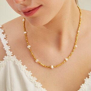 May include: A gold necklace with small, round beads and white pearls. The necklace is delicate and feminine.