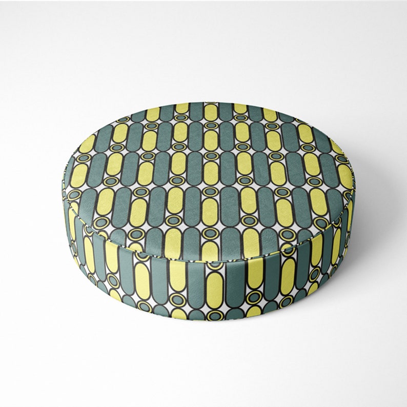 May include: A round, yellow and teal patterned floor cushion. The cushion has a geometric pattern of vertical lines and circles.