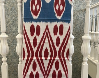 Könnte beinhalten: Ein weißer und blauer Ikat-Stoff mit rotem Muster. Der Stoff hat ein sich wiederholendes Muster aus Kreisen und Rauten.