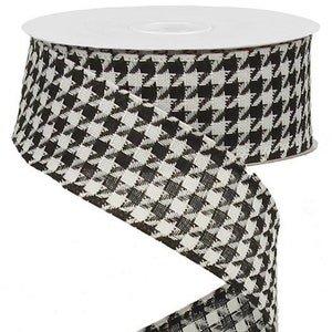 May include: A roll of decorative ribbon with a black and white houndstooth pattern. The ribbon is tightly wound on a white spool, with a length of the ribbon unwound and spiraling downwards. The ribbon is suitable for crafts and gift wrapping.
