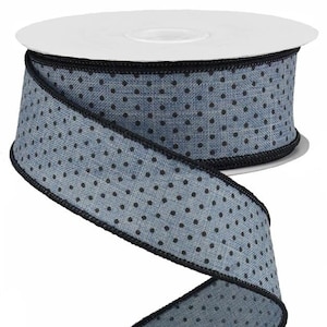 May include: A roll of blue and black polka dot ribbon with a black edge. The ribbon is made of a textured fabric.