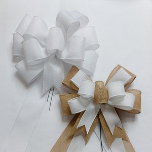 May include: Two white satin bows with tails, one with a burlap bow on top, all tied together with wire.