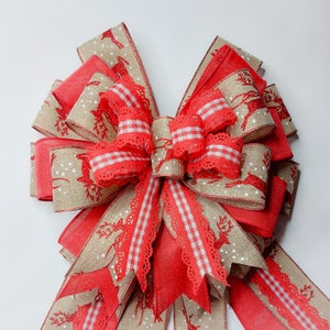 May include: A large red and brown Christmas bow with a white and red gingham ribbon and a white lace trim. The bow is decorated with a reindeer pattern.