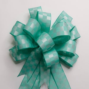 May include: A teal and white checkered ribbon bow. The bow is made of satin ribbon and has a shiny finish.
