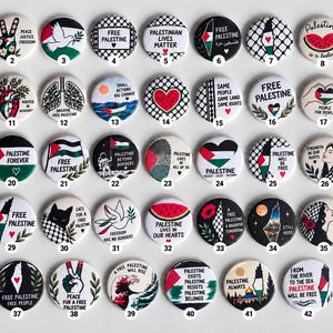 Op de afbeelding: Een verzameling van tweeënveertig ronde pins met diverse ontwerpen, illustraties en teksten gerelateerd aan Palestina, waaronder symbolen zoals watermeloenen, duiven, vlaggen en kaarten, elk genummerd van één tot tweeënveertig.