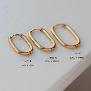 May include: Three gold-colored oval hoop earrings in small (0.63 x 0.47 inches), medium (0.71 x 0.47 inches), and large (0.79 x 0.55 inches) sizes. The earrings are displayed on a white surface. Text indicates the size of each earring.