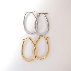 May include: Two pairs of teardrop-shaped hoop earrings. One pair is finished in a polished silver tone, and the other pair is finished in a polished gold tone. Each earring features a hinged post closure at the top for secure attachment.