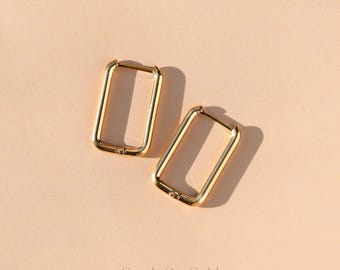 May include: Two gold-colored rectangular hoop earrings. The earrings are displayed on a light peach-colored surface. The text "Crush On Gold" is at the bottom of the image.